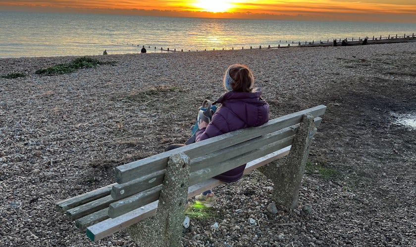 Kate sitting on a bench at the beach