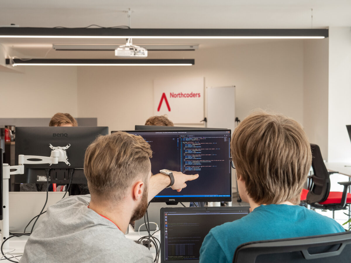 Two people programming, Northcoders logo in the background